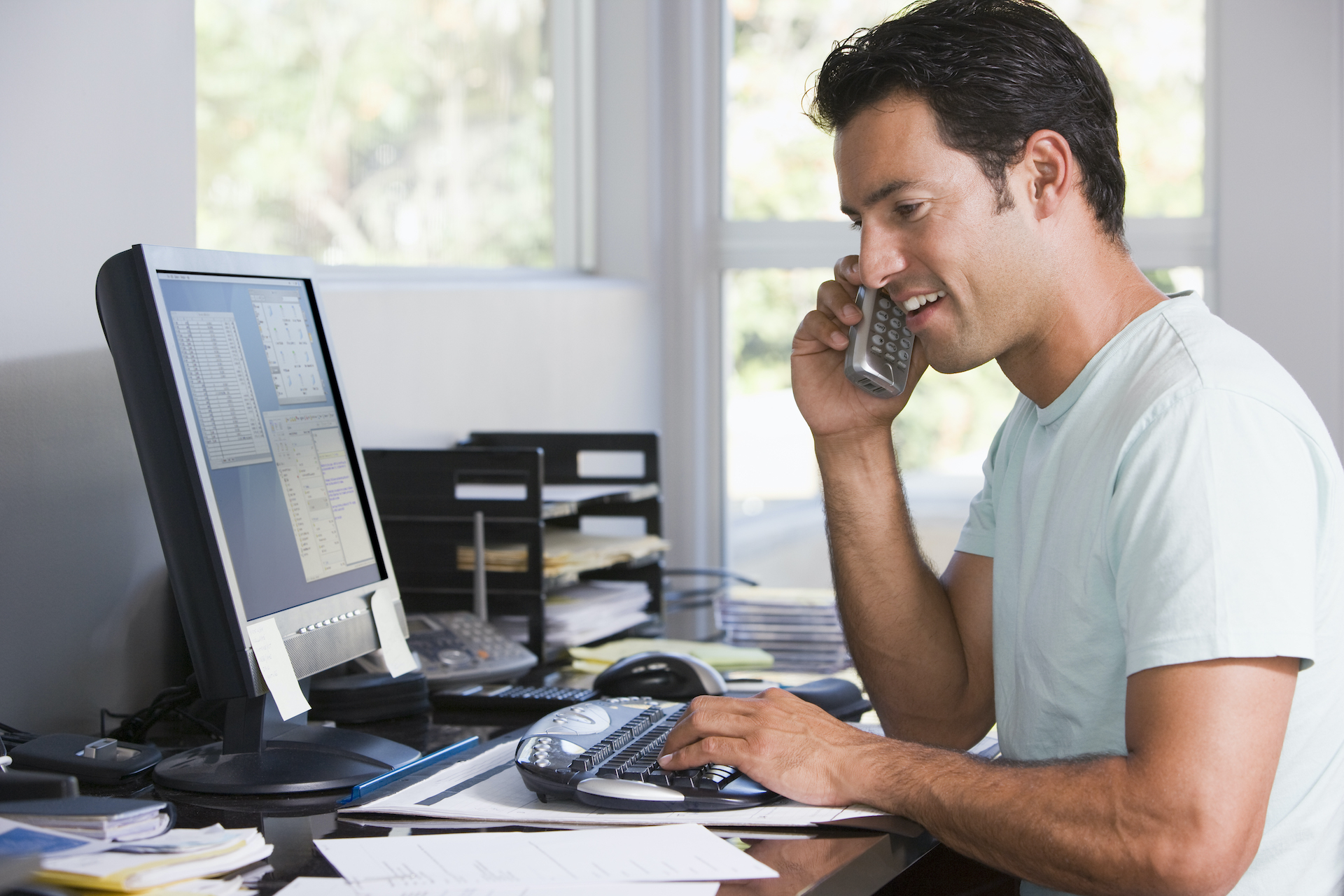 Man talking on a telephone at his computer